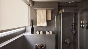 A modern bathroom with a glass shower enclosure, a towel rack, and a small shelf with toiletries.