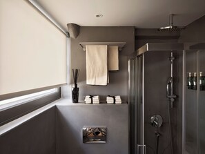 Un baño moderno con cabina de ducha de vidrio, un perchero y un pequeño estante con artículos de aseo.