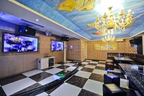 Zona de bar con suelo a cuadros, una araña y varias pantallas.