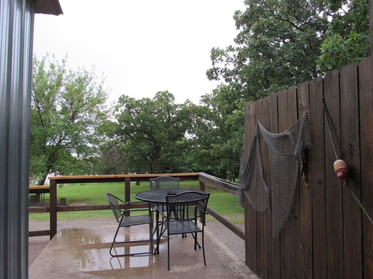 Un patio al aire libre con cubierta de madera, una mesa, sillas y una hamaca.