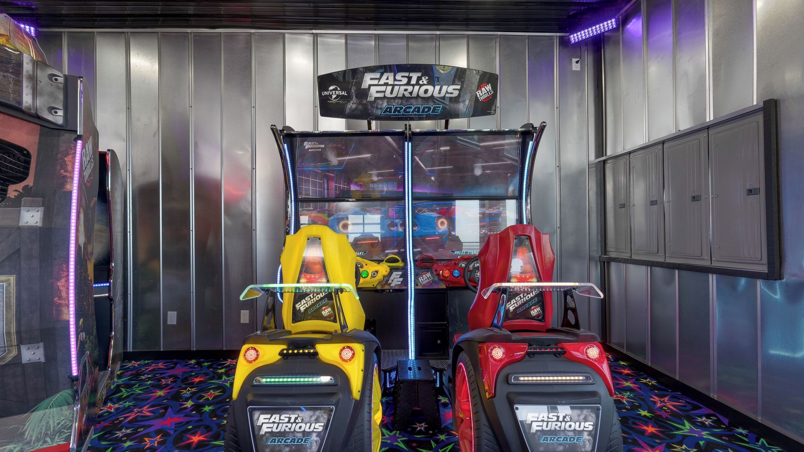 A room with arcade racing games, a metallic wall, and a star-patterned floor.