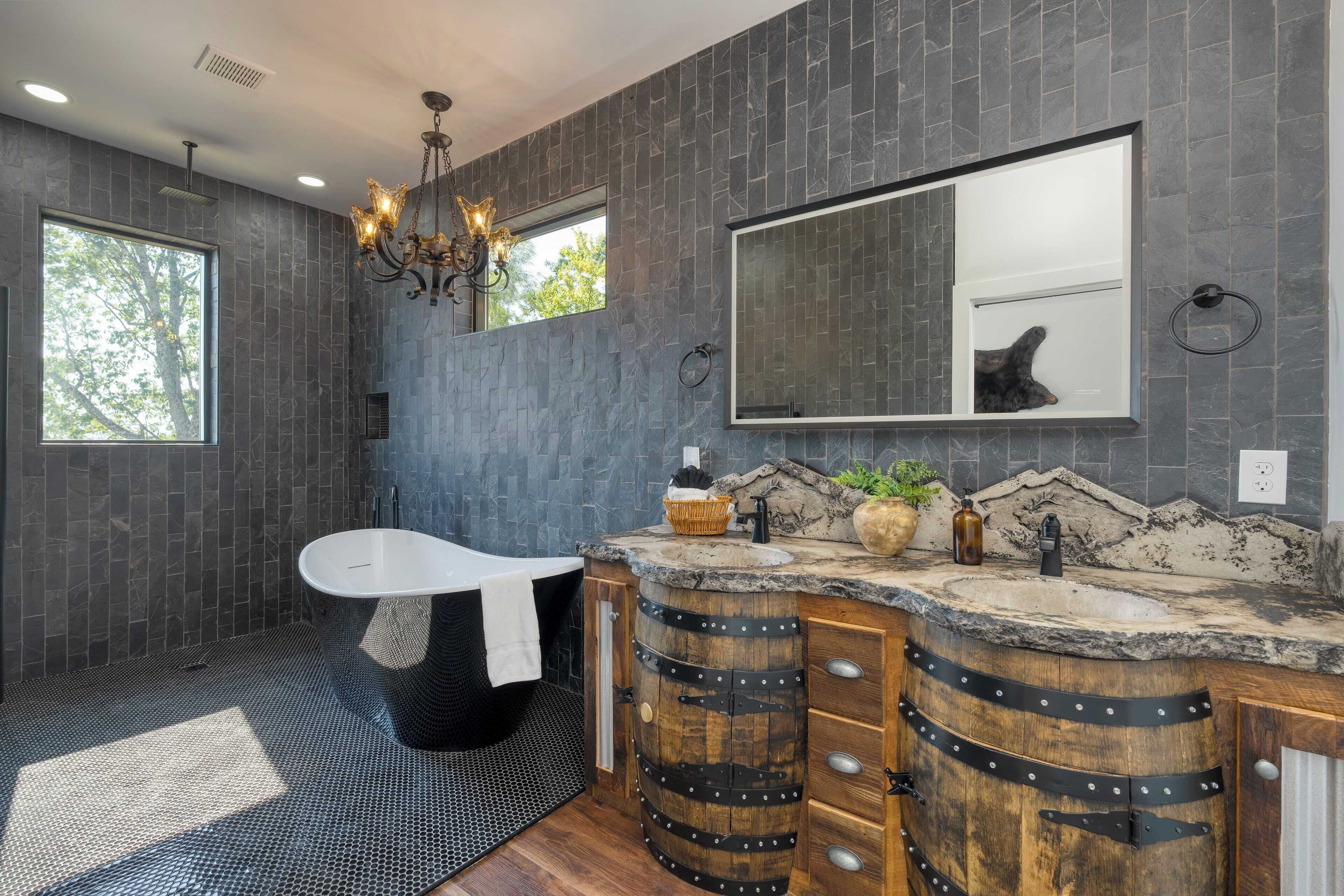 A modern bathroom with a freestanding bathtub, a large mirror, and a stone countertop.