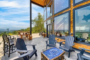 Ein Sitzbereich im Freien mit Adirondack-Stühlen und einem Mosaik-Tisch, mit Blick auf eine schöne Landschaft.