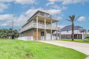 A two-story house with a balcony, a garage, and a well-maintained lawn. - Walk to Sea Isle Beach! Canal-Front Gem w/ Pool (Galveston)