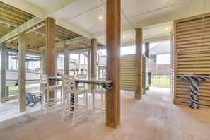 A covered outdoor area with wooden beams, a table, and chairs. - Walk to Sea Isle Beach! Canal-Front Gem w/ Pool (Galveston)