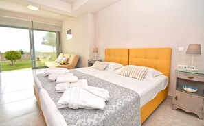 Een moderne slaapkamer met een groot bed, een bank en een glazen deur naar een tuin.