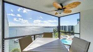 A balcony with a table and chairs, overlooking a body of water and a cityscape. - Marco Island Condo w/ Balcony + Water Views! (Marco Island)