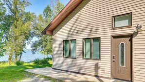 A house with a brown door, two windows with shutters, and a small porch area. - Lake Champlain Retreat w/ Grill, Fire Pit! (Chazy)