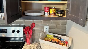 A kitchen with a microwave, a coffee maker, and a toaster. There are plates, a can of soup, and a jar of peanut butter on the shelves. - My Peaceful Place (Burleson)