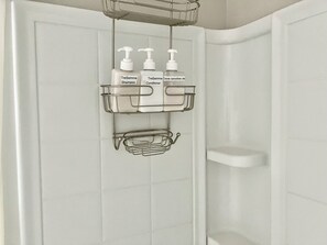Bathroom features a shelf unit and a metal shower caddy.