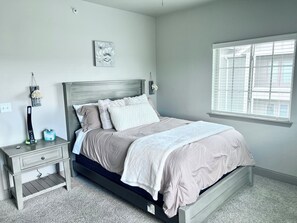 Cozy retreat with a single bed, nightstand, and window with blinds.