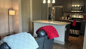 A modern kitchen with dark cabinets, stainless steel appliances, and a central island. - My Peaceful Place (Burleson)