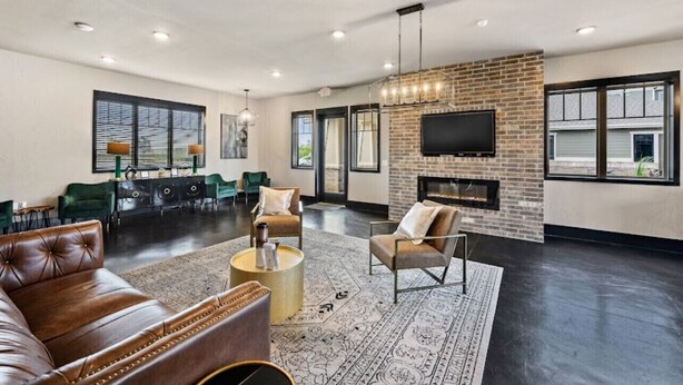 A spacious living room with a leather sofa, a fireplace, and a television mounted on a brick wall. - My Peaceful Place (Burleson)