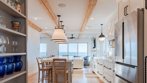 Una cocina moderna con vigas de madera, electrodomésticos de acero inoxidable y vista al mar.