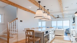 Una cocina moderna con piso de madera, una isla central e iluminación colgante.