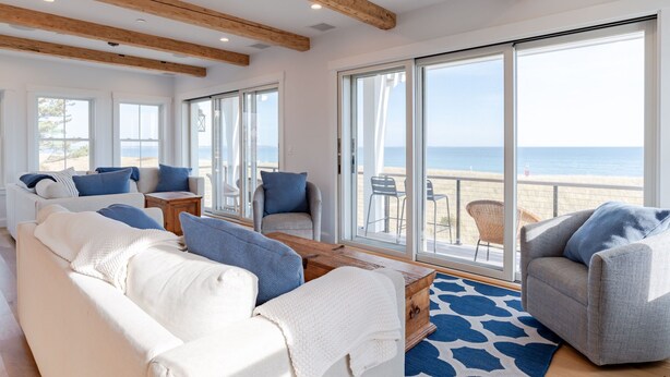 Amplia sala de estar con un gran ventanal corredera que da a un balcón con vista a la playa.