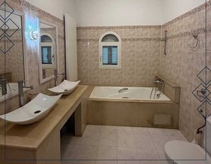 Une salle de bain avec une grande baignoire, deux lavabos et des toilettes.