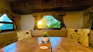 A kitchen area with a granite countertop, a small potted plant, and a book on the table. - Ramblin' Rose: a sweet Glamper for 2 under the stars in Dripping Springs (Dripping Springs)