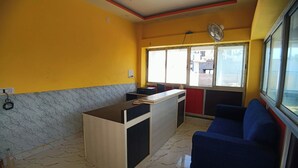 Ένα δωμάτιο με μαρμάρινο δάπεδο, ένα ξύλινο γραφείο, έναν μπλε καναπέ και ένα παράθυρ ο με θέα σε κτίρια.