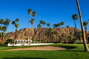 A golf course with palm trees and a mountain in the background.