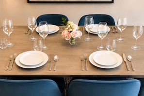 Mesa para dos, con platos blancos, cubiertos y copas de vino transparentes.