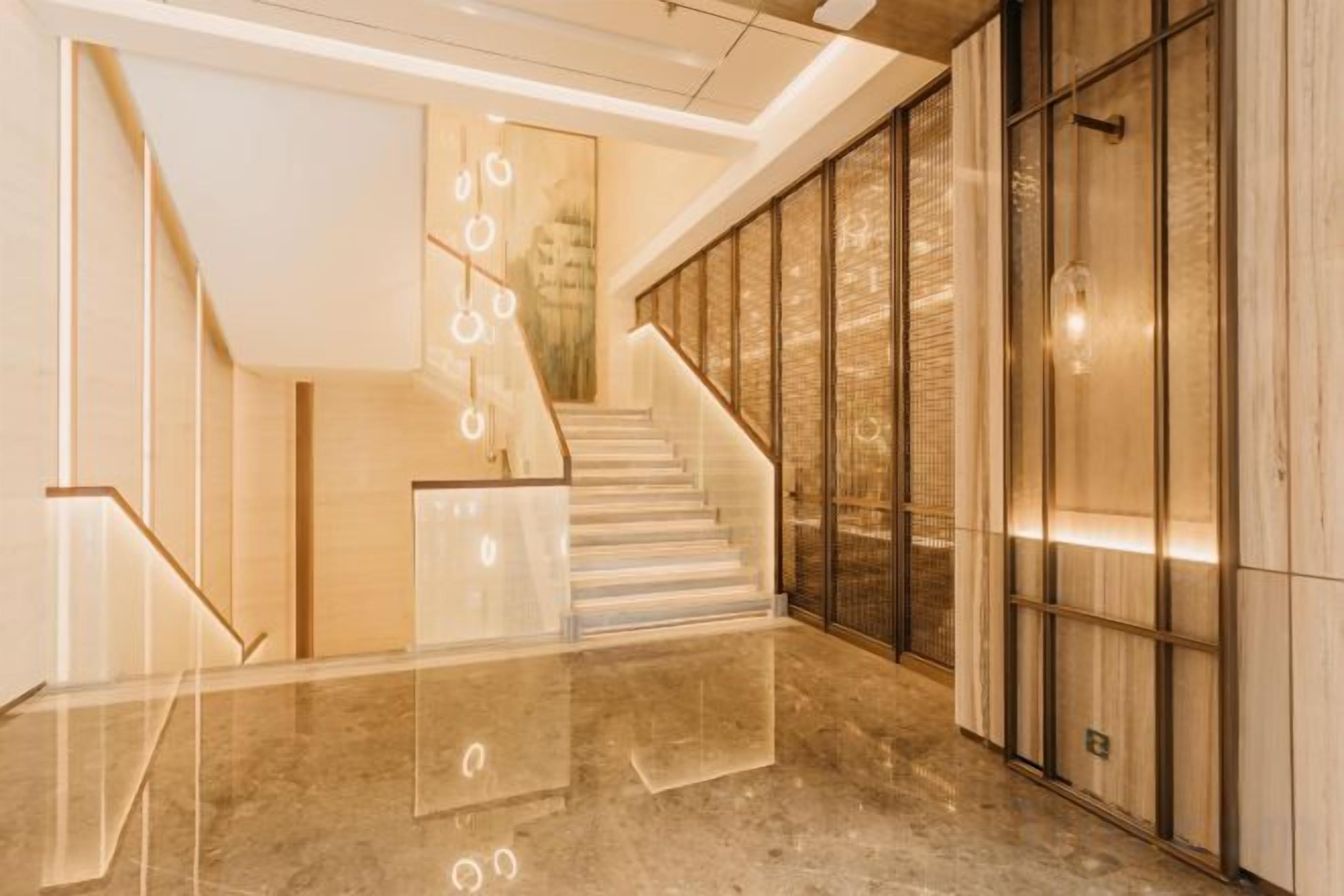 A modern interior with a staircase, glass railings, and a polished floor.