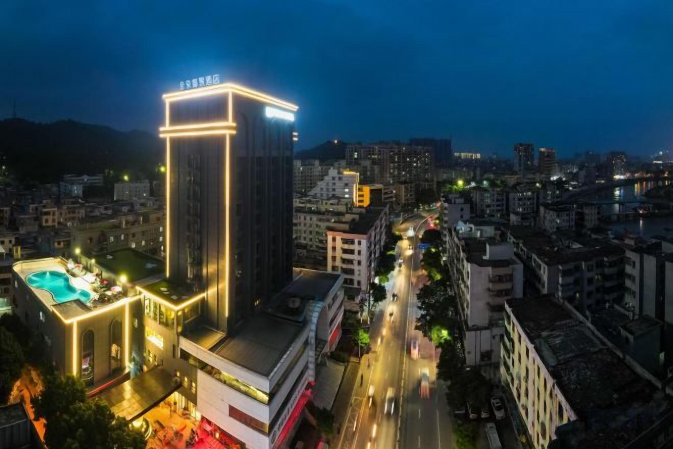 A high-rise hotel with a swimming pool, multiple floors, and a cityscape in the background.