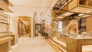 A modern hotel lobby with a marble floor, a reception desk, and a seating area with tables and chairs. - Jinquan Yujing Hotel (Enping)