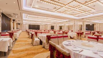A banquet hall with round tables, red sashes, and a carpeted floor.