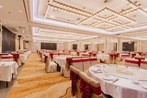 A banquet hall with round tables, red sashes, and a carpeted floor. - Jinquan Yujing Hotel (Enping)