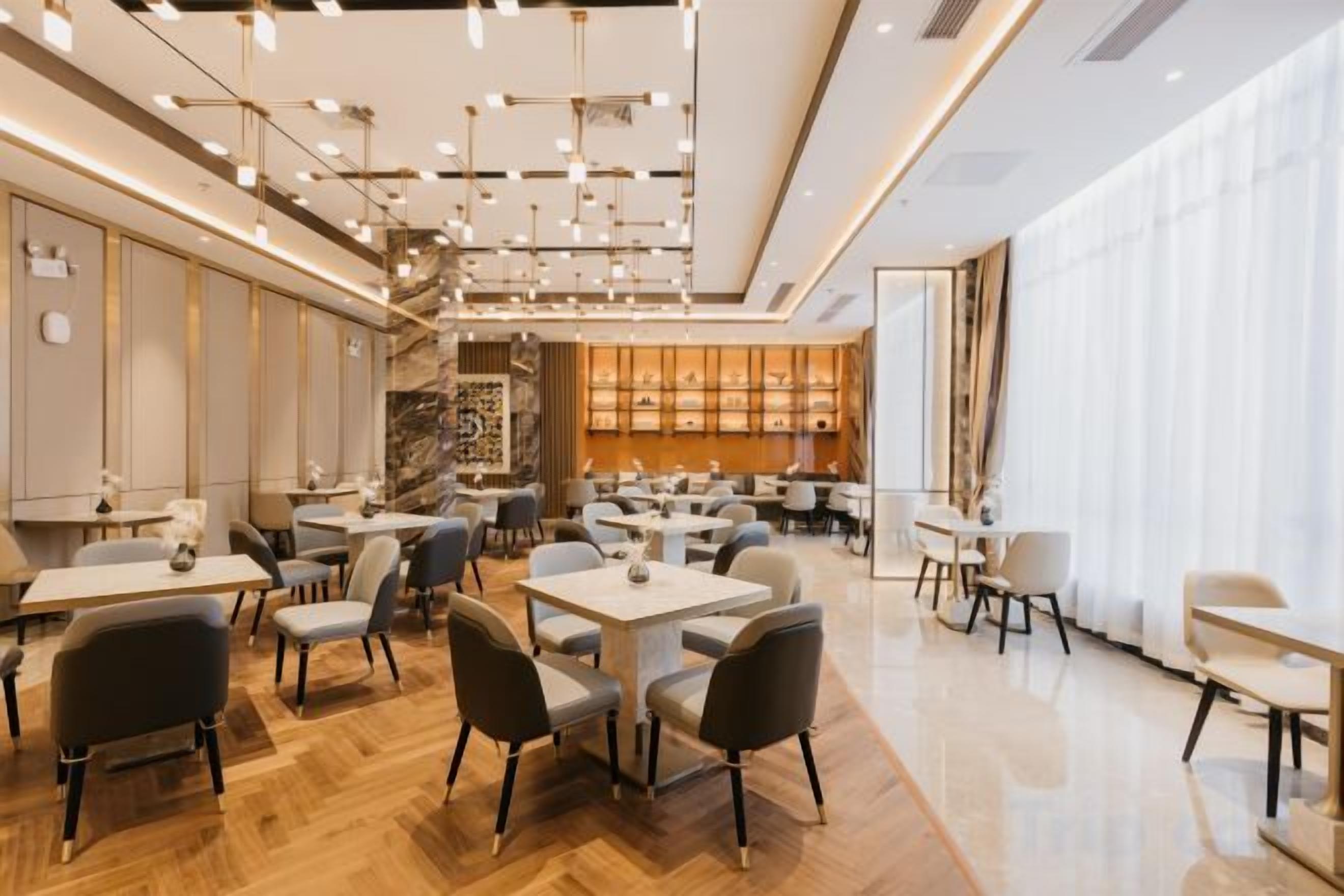 A modern restaurant interior with multiple dining tables and chairs, a bar area, and a staircase leading to an upper level.