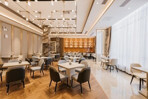 A modern restaurant interior with multiple dining tables and chairs, a bar area, and a staircase leading to an upper level. - Jinquan Yujing Hotel (Enping)