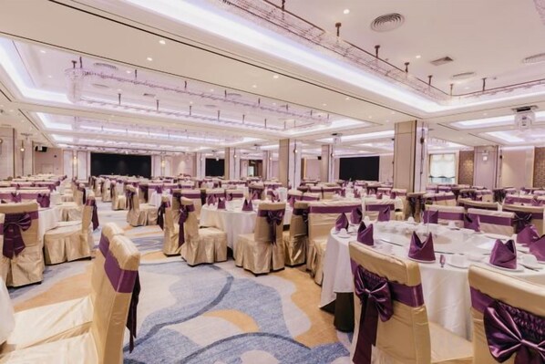 A banquet hall with round tables, chairs, and a stage. - Jinquan Yujing Hotel (Enping)