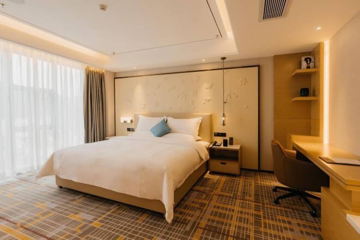 Ein Hotelzimmer mit einem großen Bett, Nachttischen, einem Schreibtisch und einem Sessel.