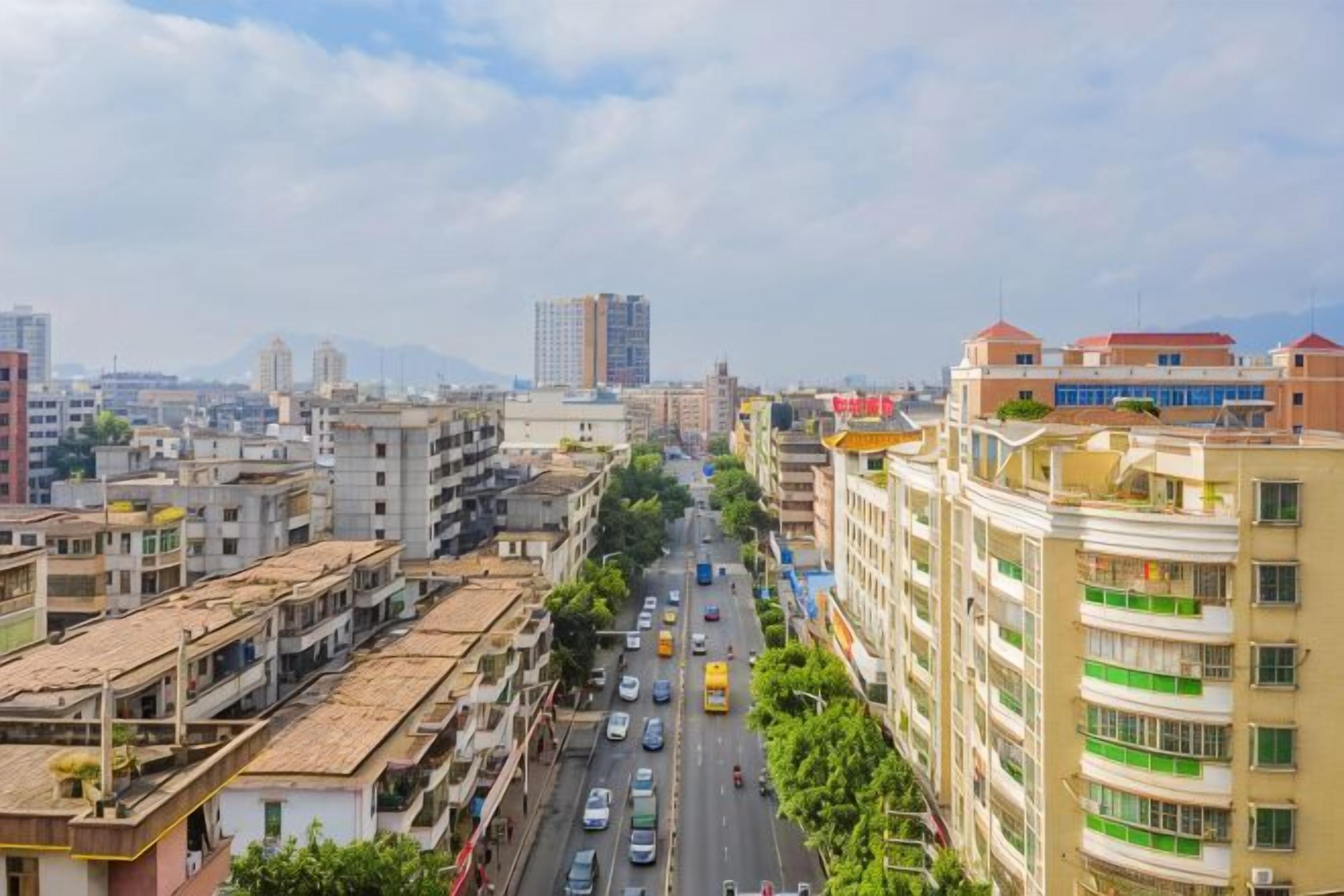 A cityscape with multi-story buildings, a busy street, and distant mountains.