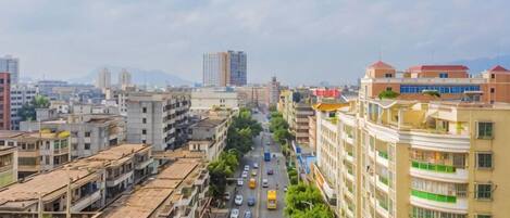 A cityscape with multi-story buildings, a busy street, and distant mountains.