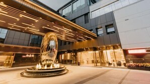 A modern building with a large metallic sculpture in front. - Jinquan Yujing Hotel (Enping)