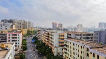 Un paisaje urbano con edificios de varios pisos, una calle con vehículos y un cielo despejado.