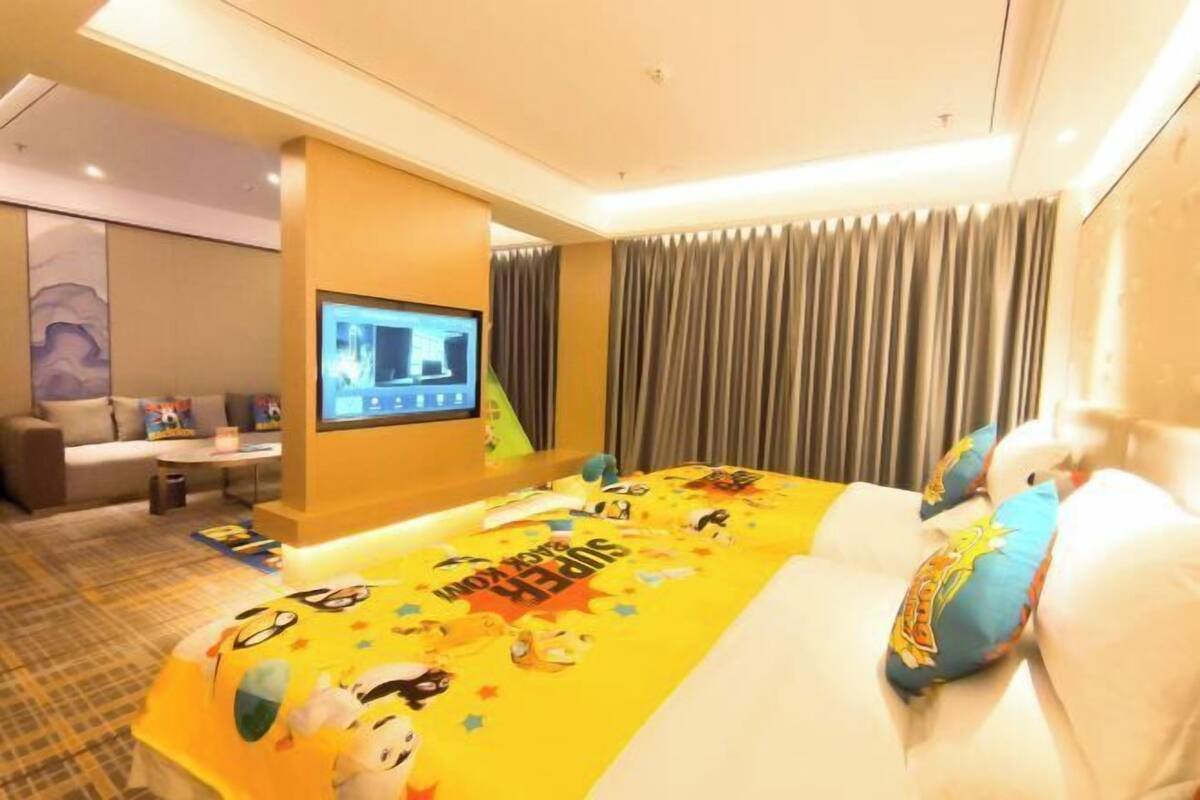Ein Hotelzimmer mit Bett, Fernseher, Sofa und Vorhang.
