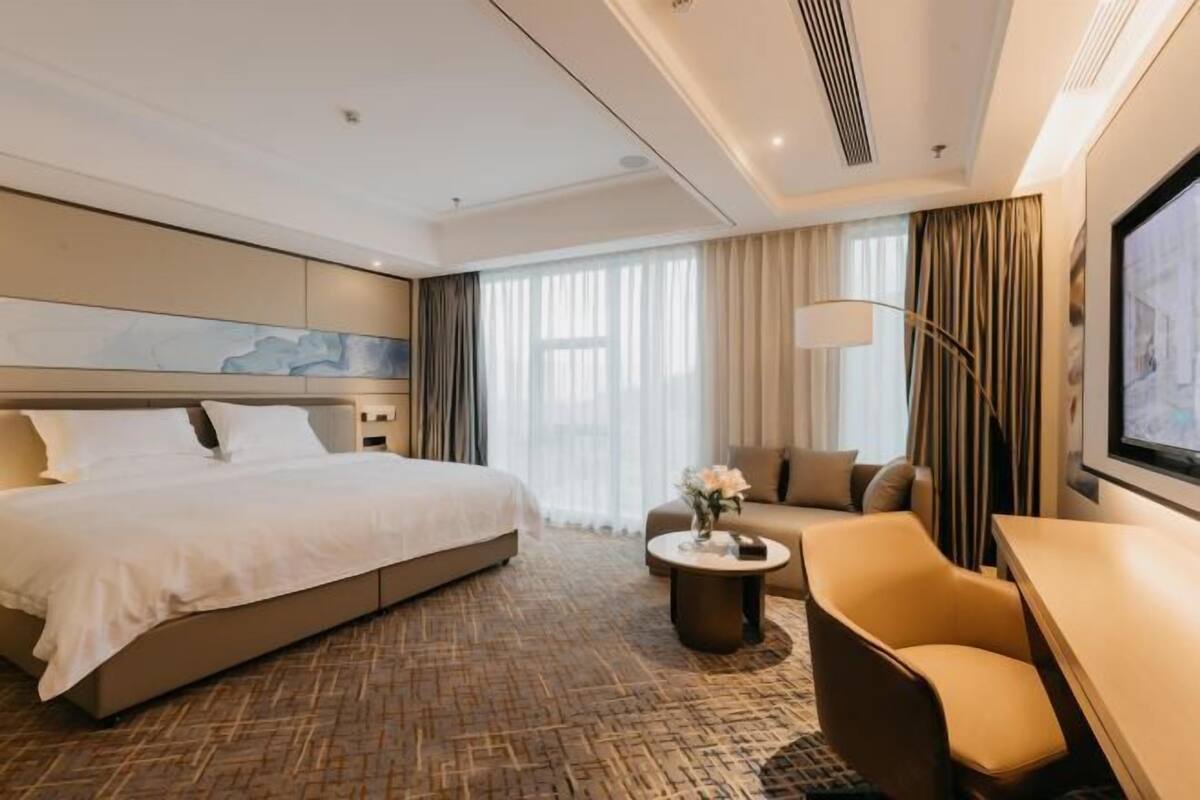 Ein Hotelzimmer mit einem großen Bett, einem Schlafsofa, einem kleinen Tisch und einem Fernseher.