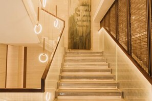 A staircase with a glass railing, a wooden handrail, and circular light fixtures. - Jinquan Yujing Hotel (Enping)