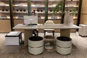 A modern office space with a large table, two chairs, a computer, and decorative plants. - Jinquan Yujing Hotel (Enping)