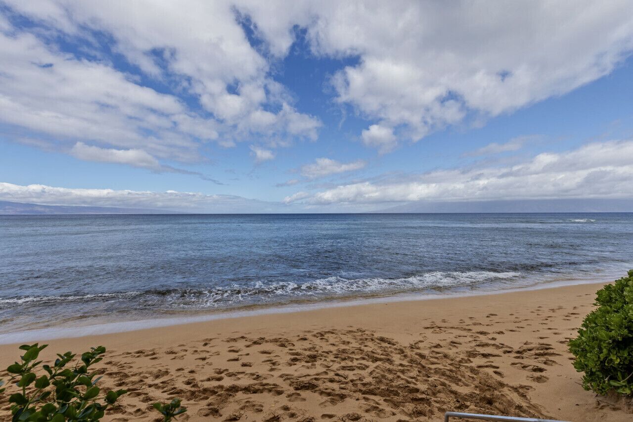 Une plage avec des empreintes de pas dans le sable et un ciel dégagé.