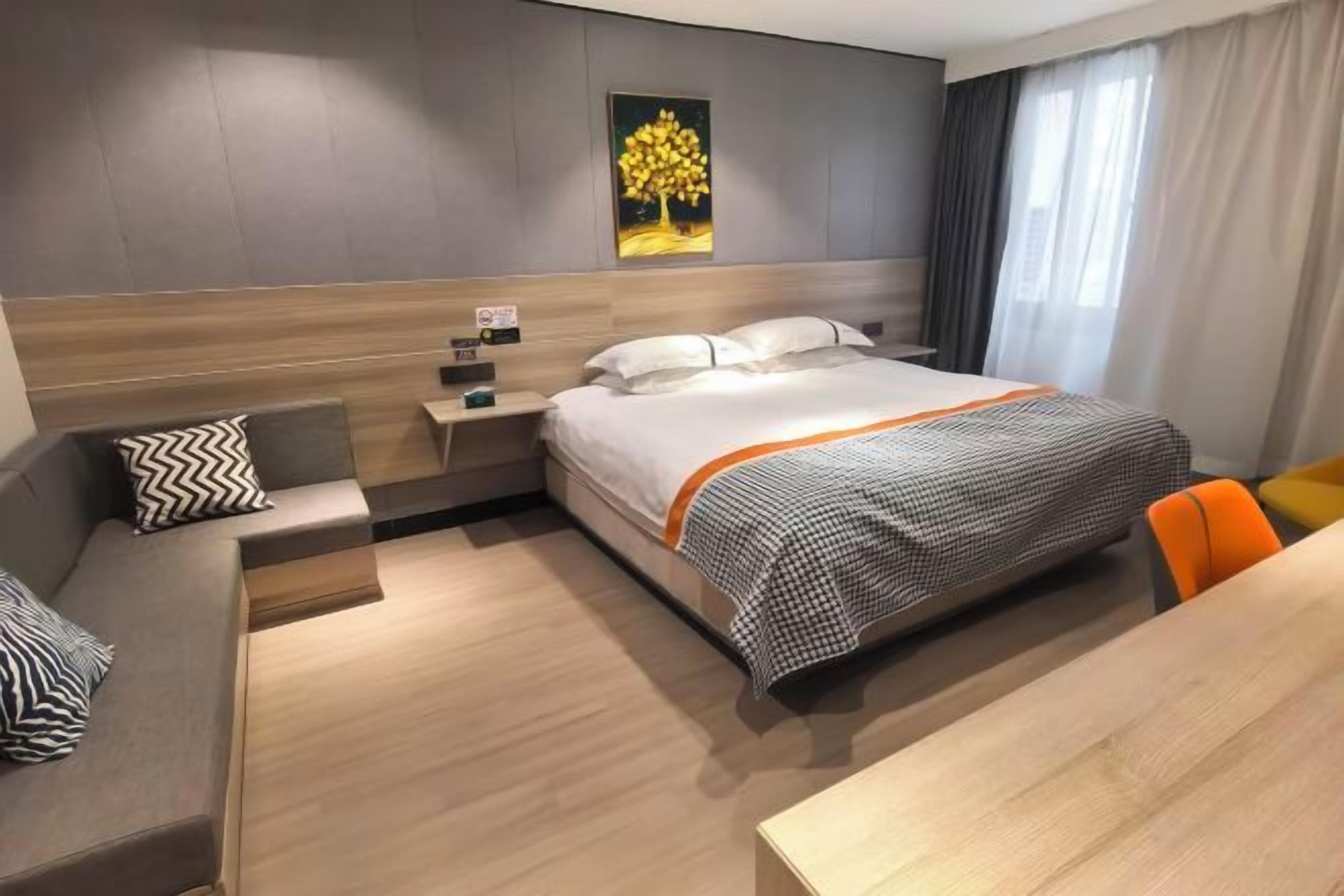 A hotel room with a bed, a nightstand, a seating area with a sofa and chair, and a painting on the wall.