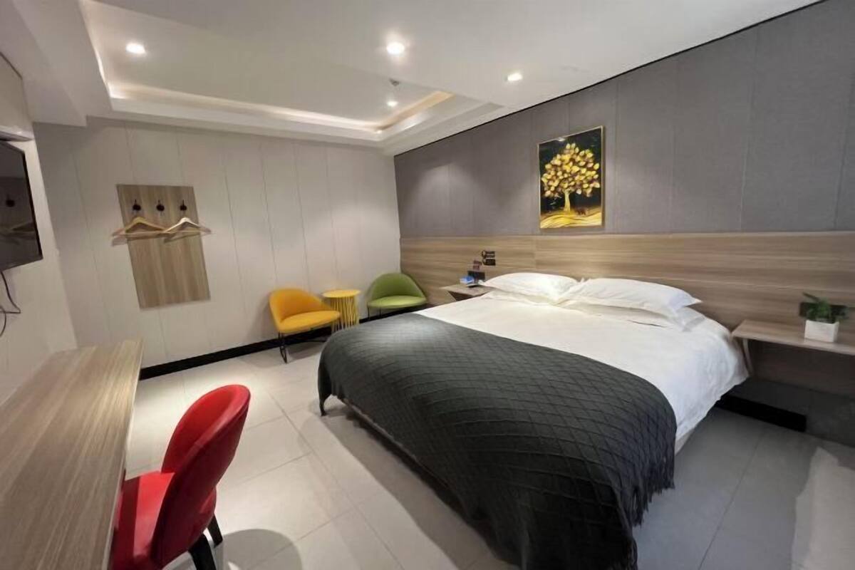 Une chambre d’hôtel moderne, équipée d’un lit, d’un bureau et de chaises.