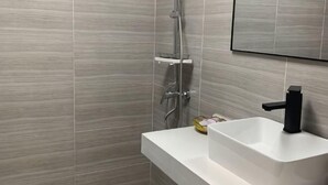 Ein modernes Badezimmer mit Dusche, einem weißen Waschbecken und einem Spiegel.