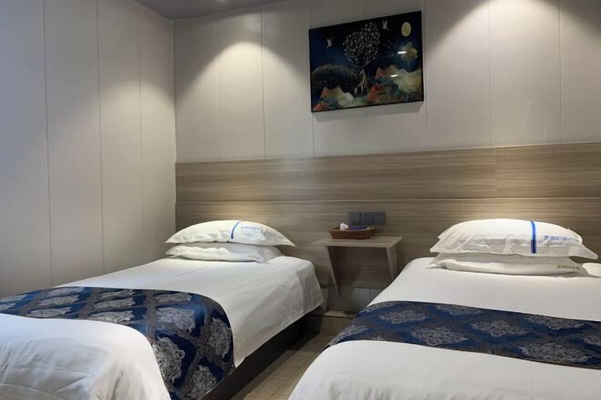 Une chambre d’hôtel avec deux lits, une table de chevet et un tableau au mur.