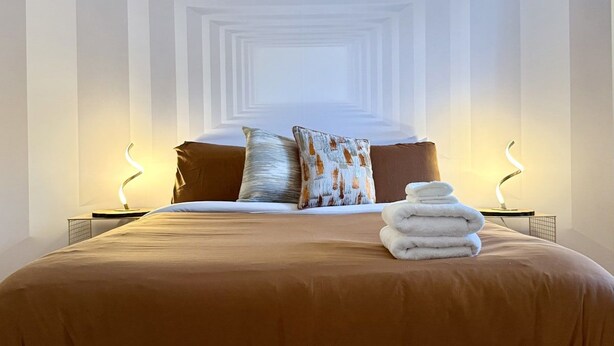 Una camera da letto con un letto grande, due lampade sui comodini e una pila di asciugamani.