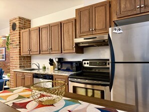 A kitchen with wooden cabinets, a stainless steel refrigerator, a microwave, and an oven.