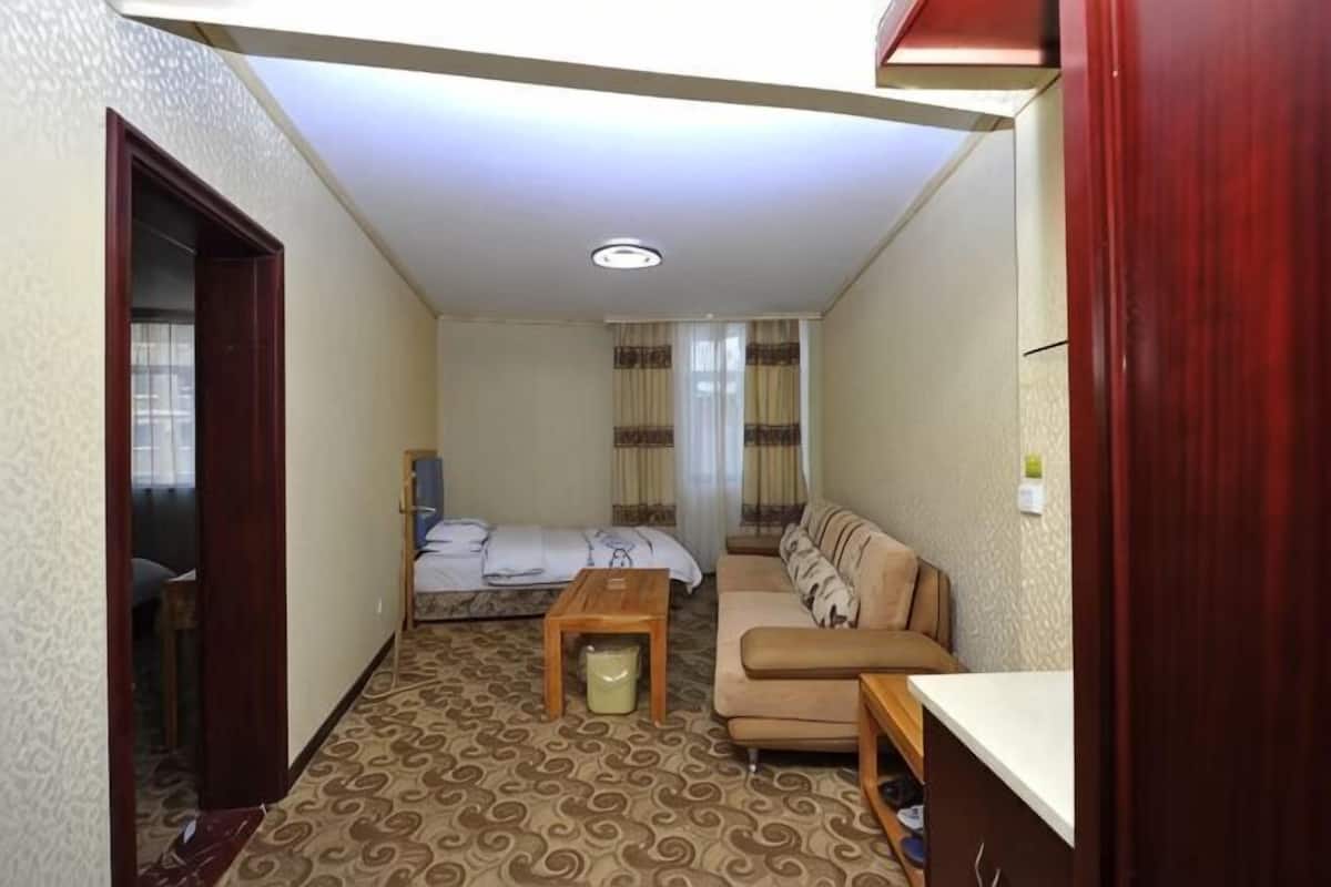 A compact hotel room with a bed, sofa, small table, and a desk.
